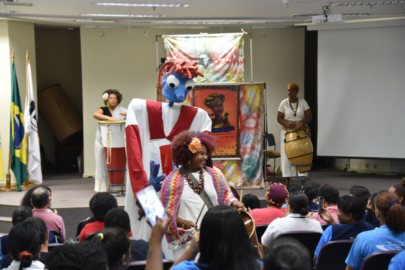 Apresentação do coletivo Ponto de Cultura Quilombo do Sopapo, com atores e bonecos dançando no palco e meio à plateia