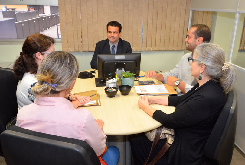 Audiência de mediação no Cejusc-JT do primeiro grau, com o juiz no centro da foto e as partes e advogados nas laterais.