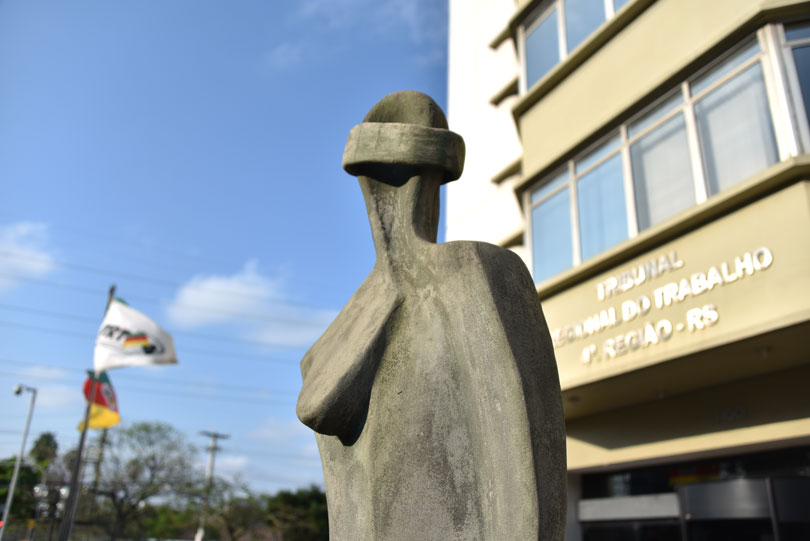 Fachada da Justiça do Trabalho da 4ª Região, com estátua da deusa Themis e entrada do prédio do Tribunal.