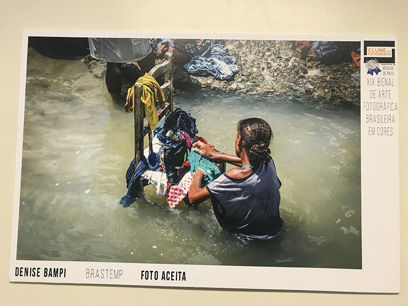 Fotografia intitulada "Brastemp" retrata uma mulher lavando roupas em um riacho