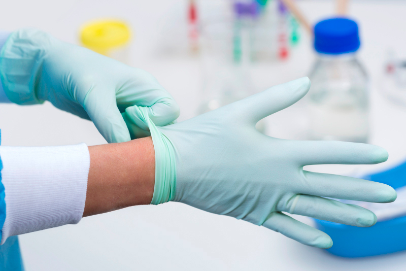 Mulher vestindo luvas de borracha em ambiente de laboratório.