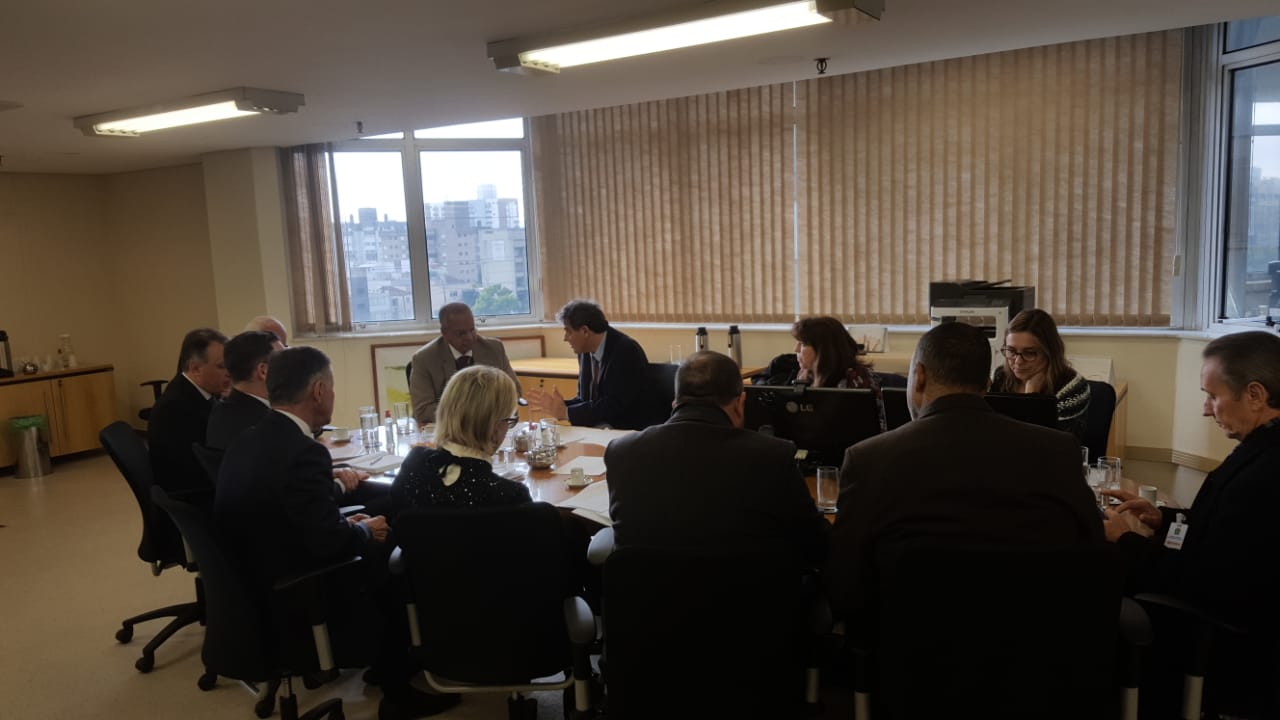 Sala de reuniões com a mesa em primeiro plano com representantes dos sindicatos e a Federação dos Metalúrgicos