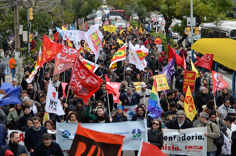 Manifestantes caminham em frente à Justiça do Trabalho.