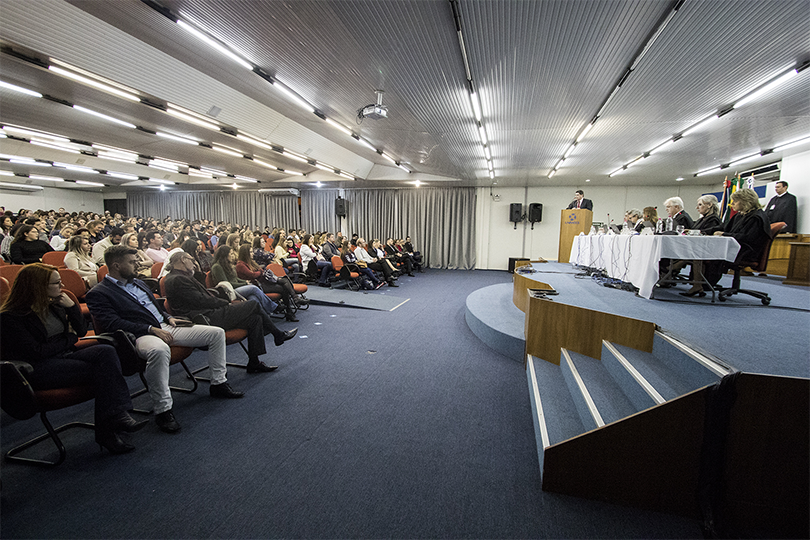 Fotografia com magistrados sentados à mesa e plateia
