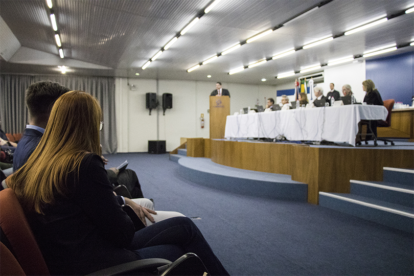 Fotografia com magistrados sentados à mesa e plateia