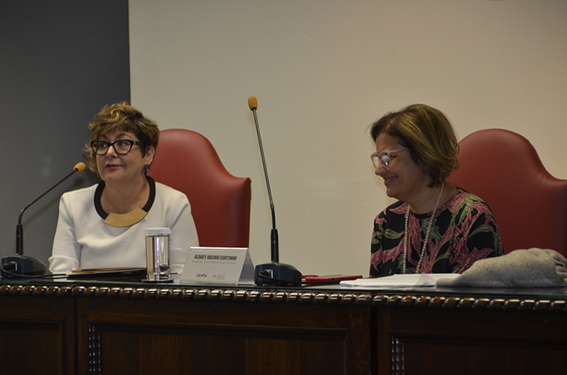 Palestrante sentado à mesa de debate discursando