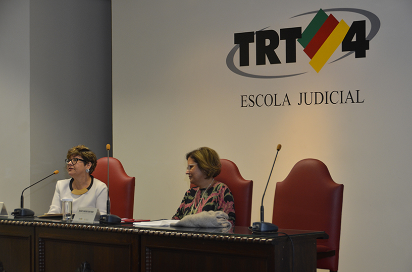 Palestrante sentado à mesa de debate discursando