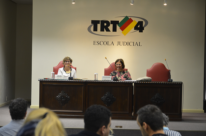 Palestrante sentado à mesa de debate discursando