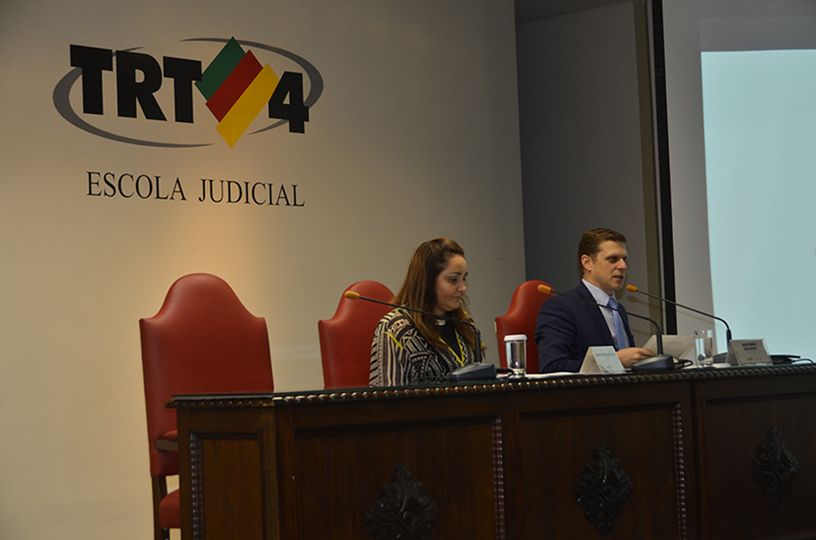 Palestrante sentado à mesa de debate discursando