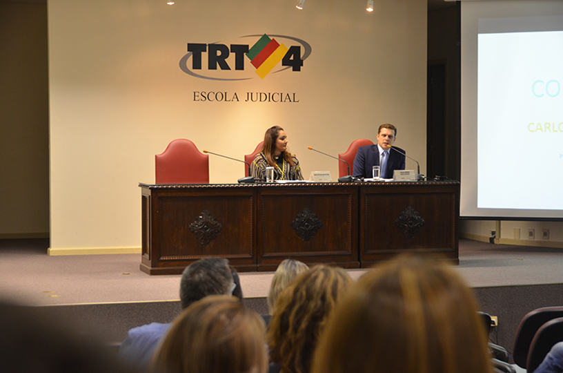 Palestrante sentado à mesa de debate discursando