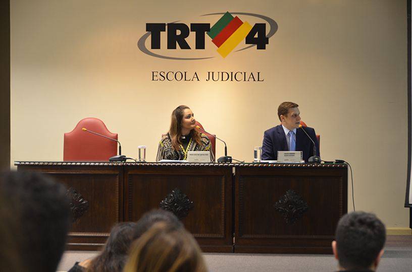 Palestrante sentado à mesa de debate discursando