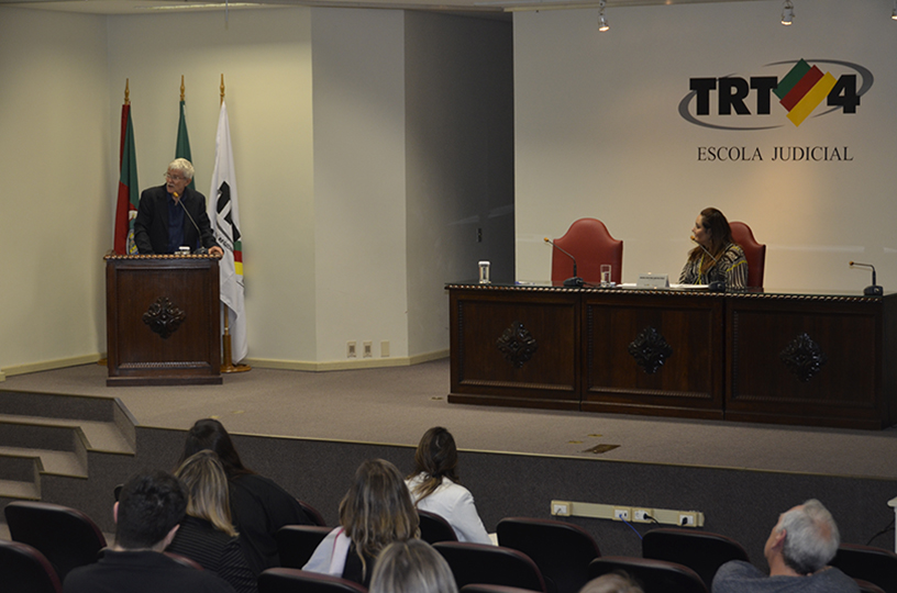 Palestrante sentado à mesa de debate discursando