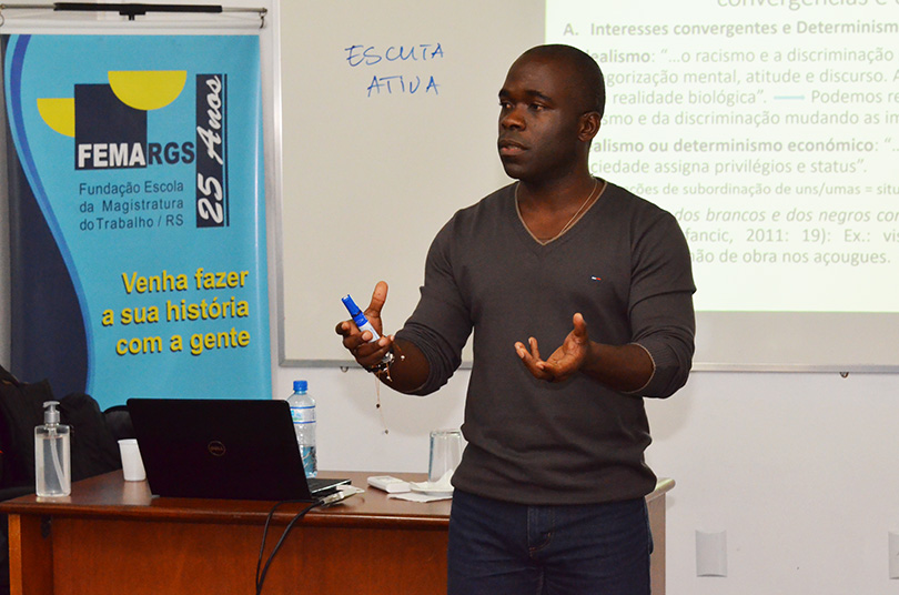 Professor Edilney ministrando o curso ao lado do cartaz da Femargs