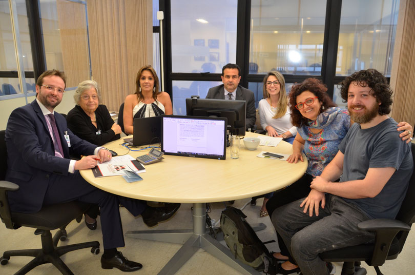Imagem dos participantes da audiência, sentados à mesa do Cejusc.