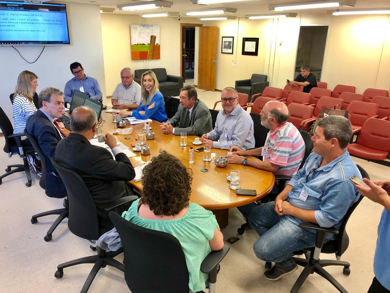Foto de todos os participantes da mediação sentados em volta de uma mesa.