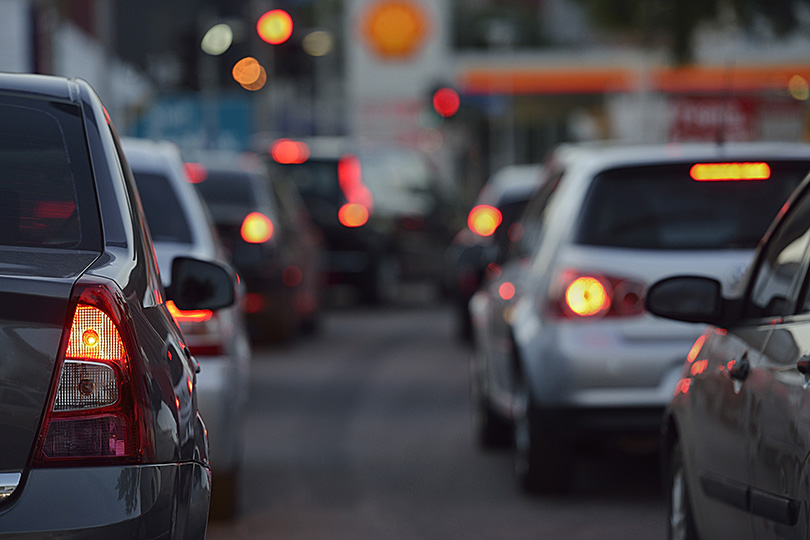 Foto de duas fileiras de carros no trânsito urbano, vistos de trás, a partir da altura da rua, como no ponto de vista de um motorista.