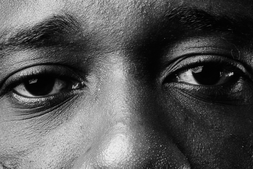 Fotografia do rosto de um homem negro com olhos demonstrando tristeza