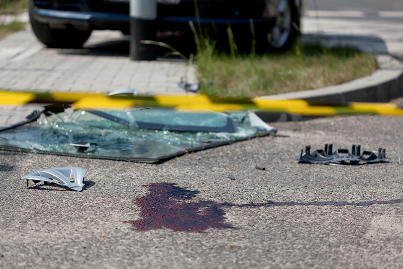 Fotografia de acidente de carro com mancha de sangue sobre a calçada