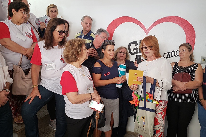 Foto da desembargadora Madalena apresentando material informativo ao público presente.