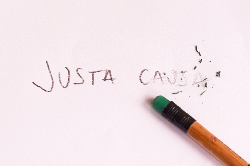 Fotografia de um papel com a expressão justa causa sendo apagada a borracha