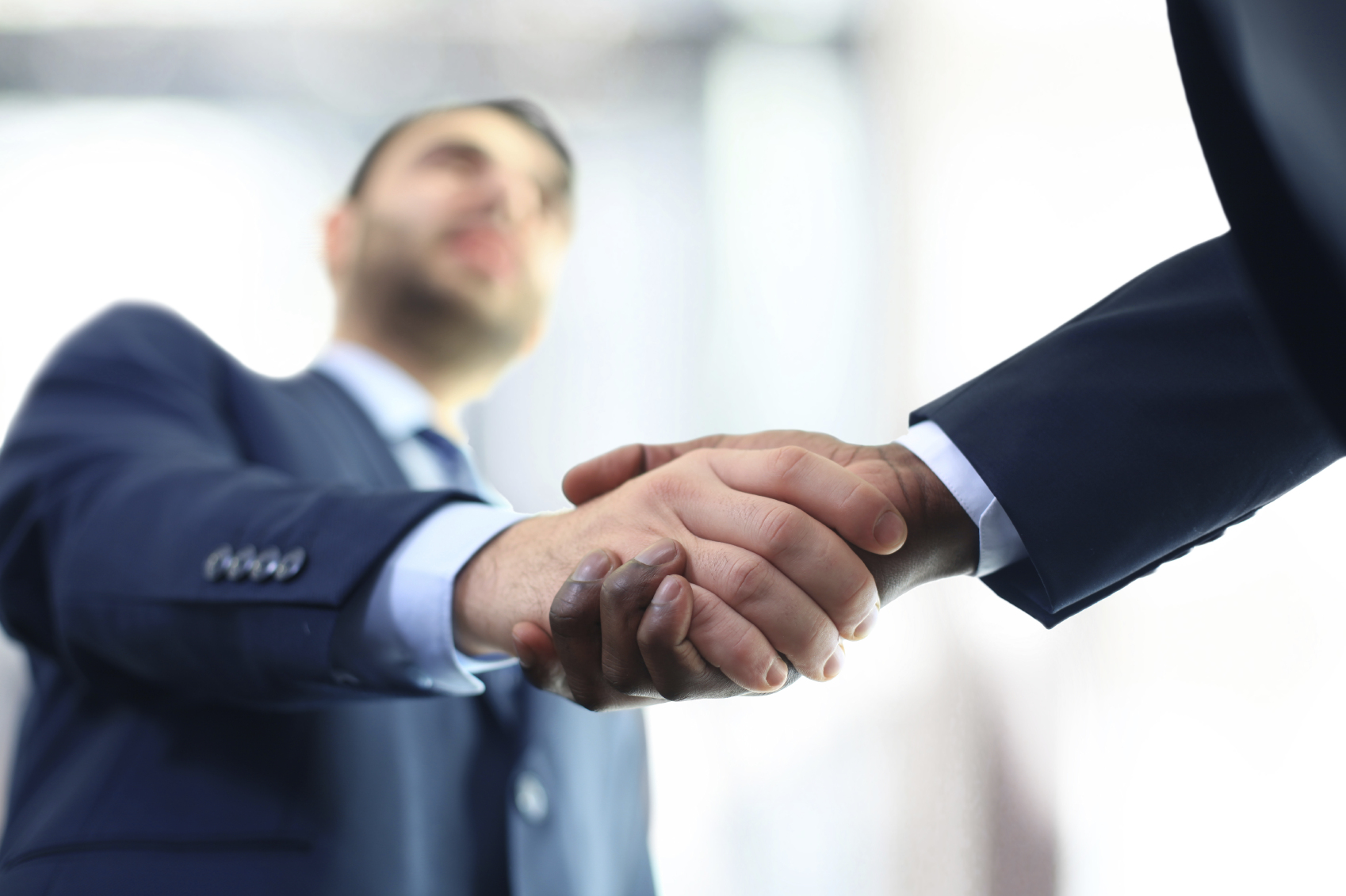 Imagem registrada de baixo para cima de um aperto de mão entre dois homens.