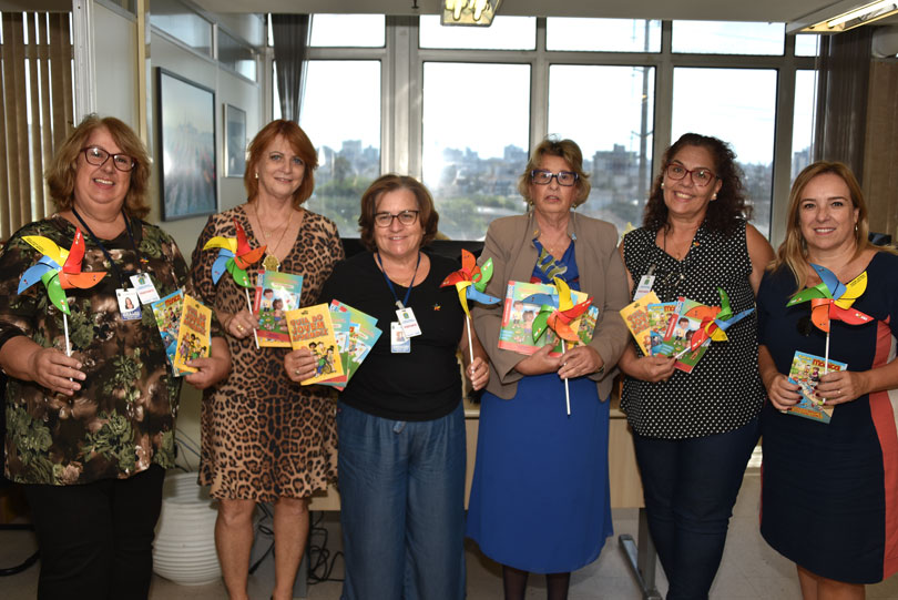 Foto das magistradas do TRT-RS e das conselheiras tutelares, com cataventos e gibis nas mãos