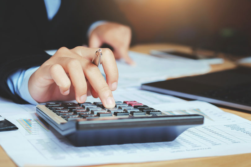 Imagem de uma mulher utilizando uma calculadora.