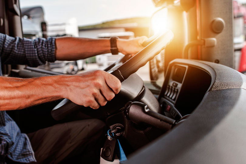 imagem de um motorista de caminhão, com as mãos no volante.