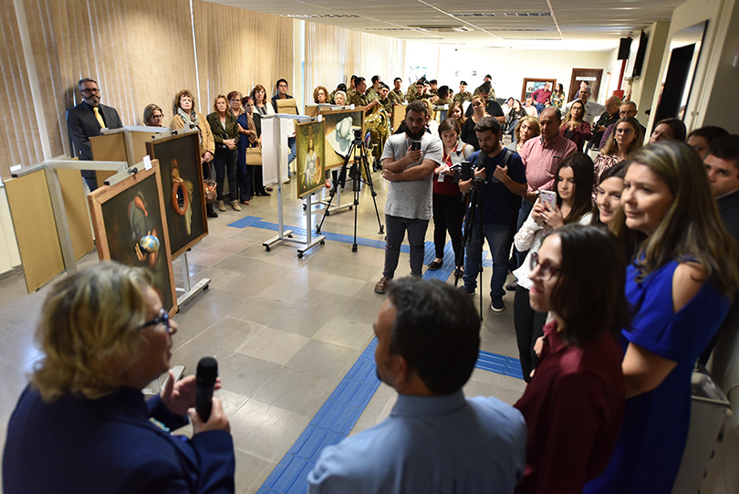 Fotografia da cerimônia de abertura da exposição, com a presidente do TRT-RS, desembargadora Vania Cunha Mattos, e convidados em primeiro plano e as obras ao fundo.