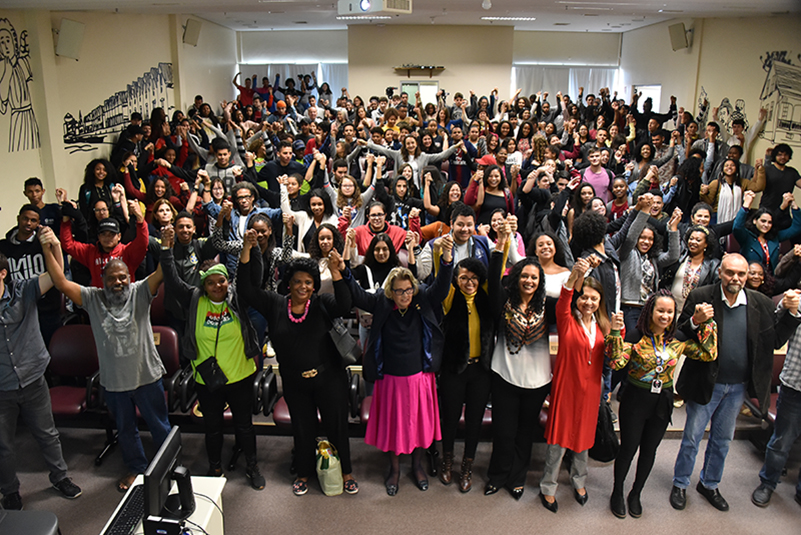Foto coletiva dos participantes do evento, mostrando o auditório lotado.