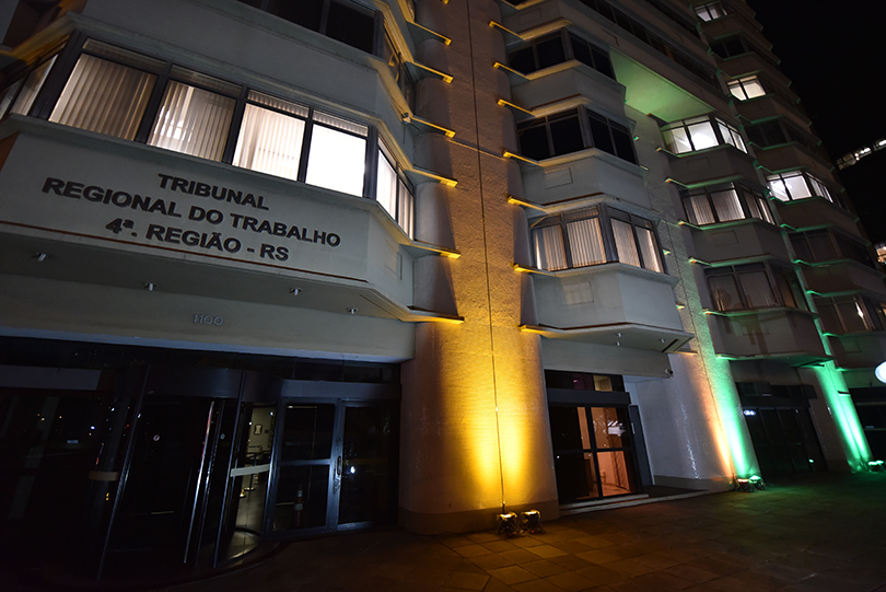 Fachada do Prédio-Sede do TRT-RS iluminada de amarelo e verde.