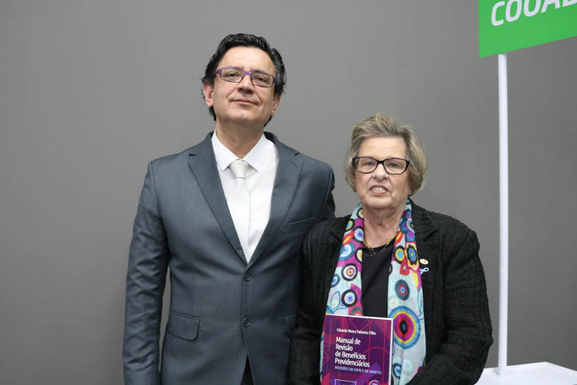 Foto posada da presidente do TRT-RS, desembargadora Vania Cunha Mattos, ao lado do autor Eduardo Rivera Palmeira Filho. A magistrada segura um exemplar do livro.