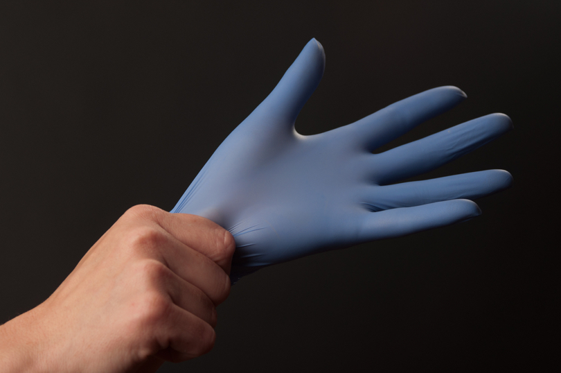 Foto de mãos colocando luva de látex