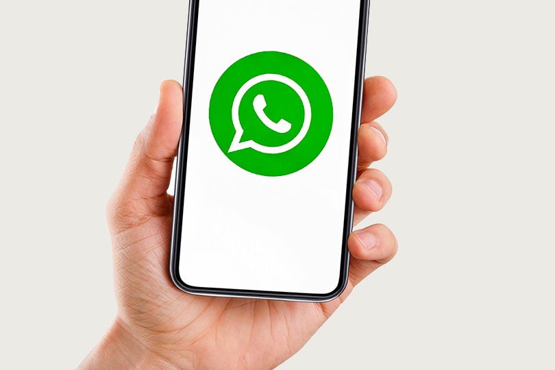 mão segurando um celular com o logo do whatsapp