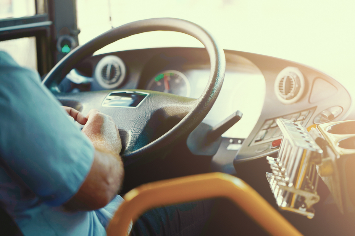 foto de um motorista com as mãos no volante de um ônibus