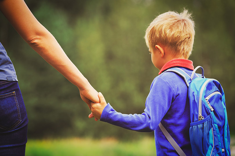 Pra Cego Ver: foto de Nadezhda1906/iStock Banco de Imagens mostra mãe levando menino para escola ou creche.