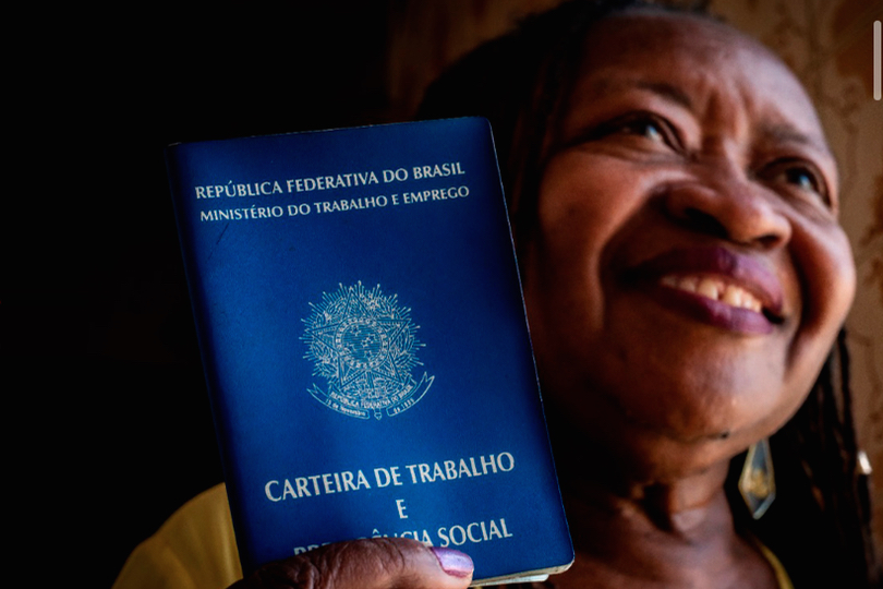 Foto ilustrativa da campanha, com trabalhadora doméstica segurando uma carteira de trabalho