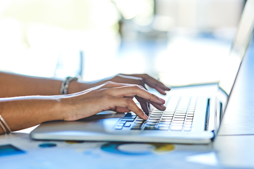 Foto das mão de uma mulher digitando em um notebook