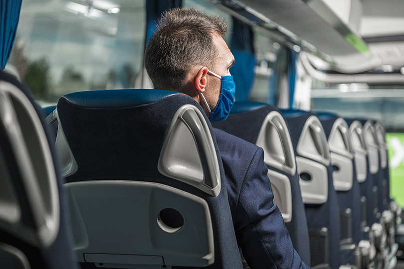 Pra Cego Ver: foto de welcomia/iStock Banco de Imagens mostra homem de costas, sentado em um micro-ônibus executivo
