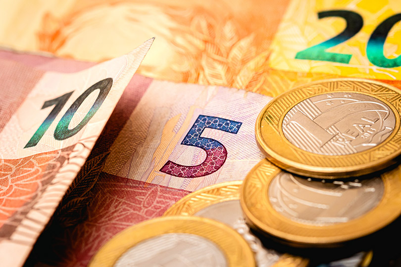 Pra Cego Ver: foto de Rmcarvalho/iStock Banco de Imagens mostra cédulas e moedas de reais
