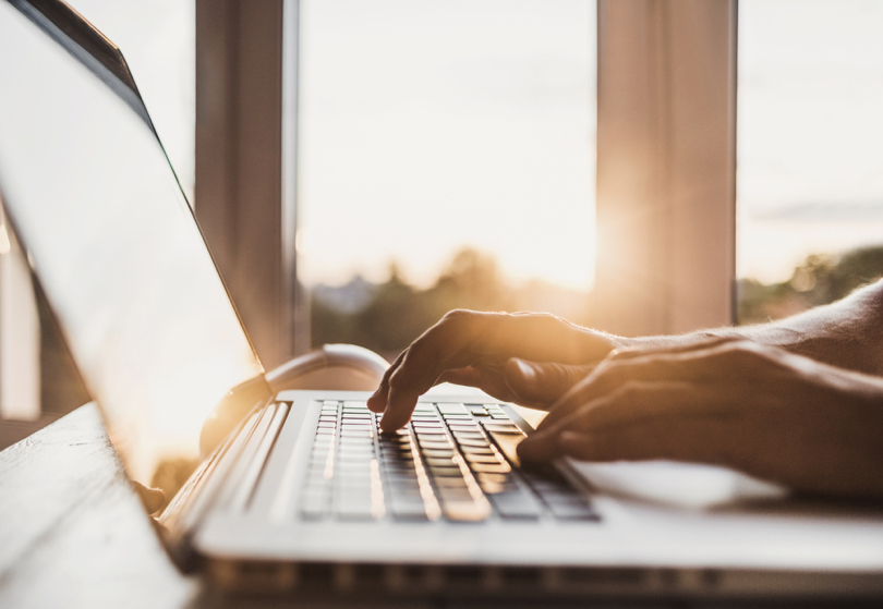 Foto das mãos de uma pessoa digitando no teclado de um notebook