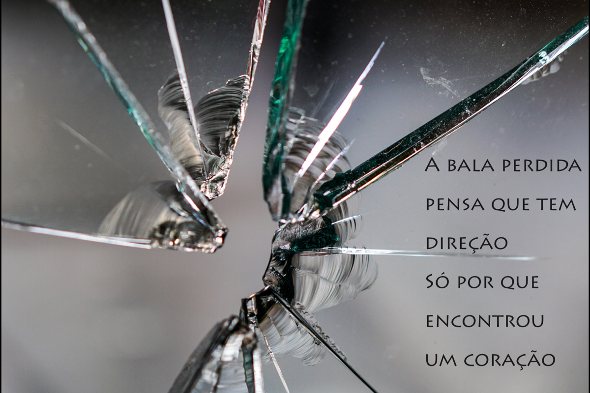 Imagem de um vidro estilhaçado. Texto: "A bala perdida/pensa que tem/direção/só por que/encontrou/ um coração"