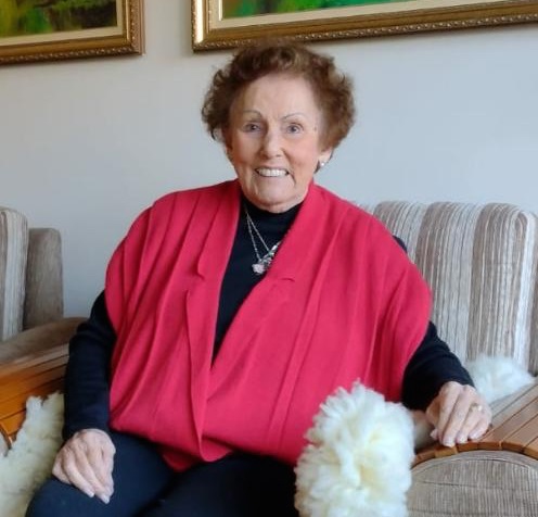 Ignesita Ferreira Lena está sentada em um sofá. Ela é uma senhora de idade avançada, de pele branca, cabelos curtos e sorriso largo. Ignesita Ferreira Lena.jpg