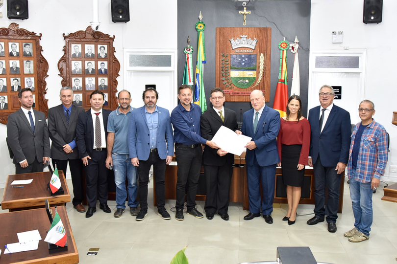 Participantes da audiência posam no plenário segurando o documento da moção pública