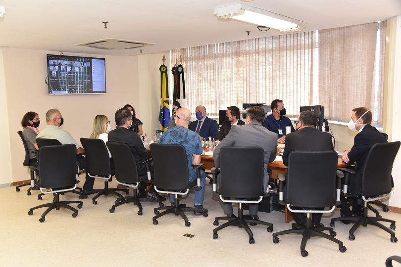 Foto da audiência, mostrando os participantes sentados à mesa de reunião.