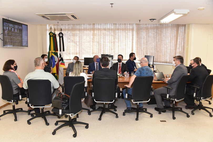 Foto da audiência, mostrando os participantes sentados à mesa de reunião.