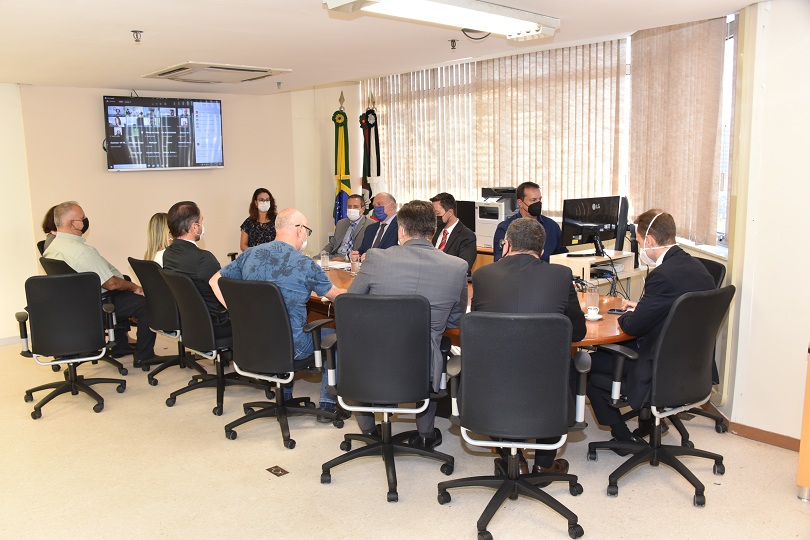 Foto da audiência, mostrando os participantes sentados à mesa de reunião.