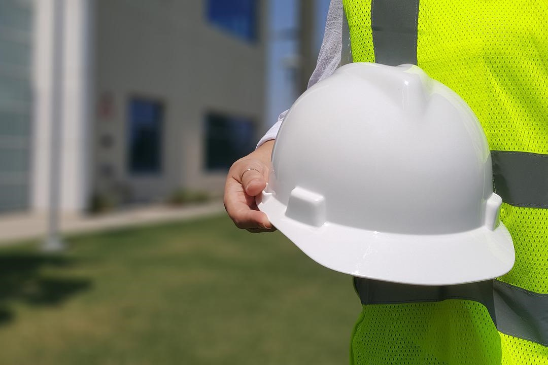 Foto de uma mão feminina segurando um capacete de proteção