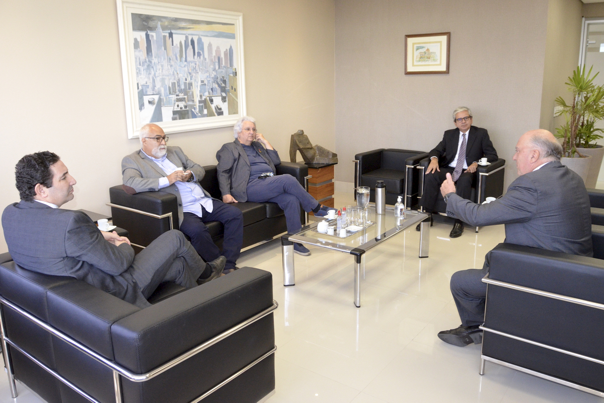 Foto dos participantes da reunião sentados em cadeiras dispostas em círculo no salão nobre da Presidência do TRT-4.
