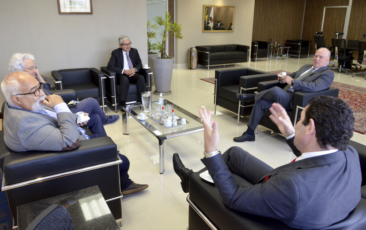 Foto dos participantes da reunião sentados em cadeiras dispostas em círculo no salão nobre da Presidência do TRT-4.